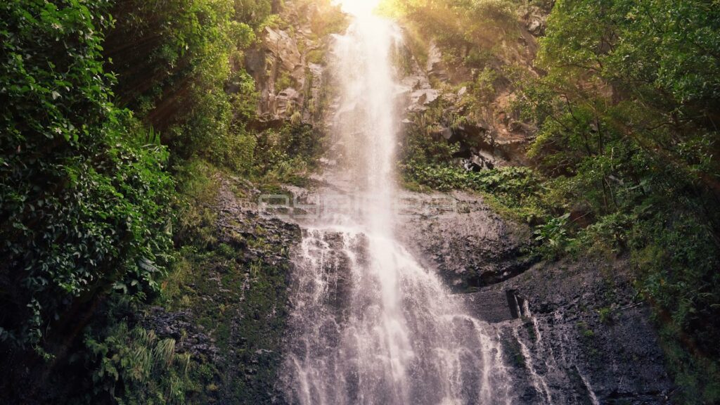 Tall Waterfall over Tiered Rocks in Hazy Sunlight