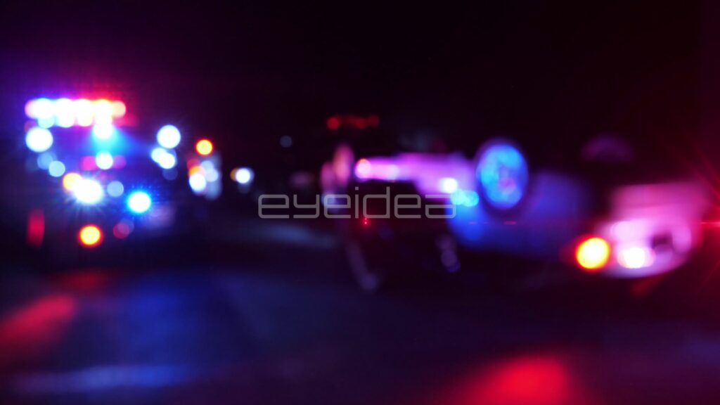 Overturned Car with Police Lights Flashing Down a Dark Road