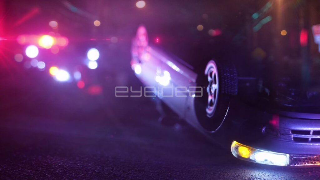 Overturned Car Resting on Its Roof Beside Flashing Patrol Lights