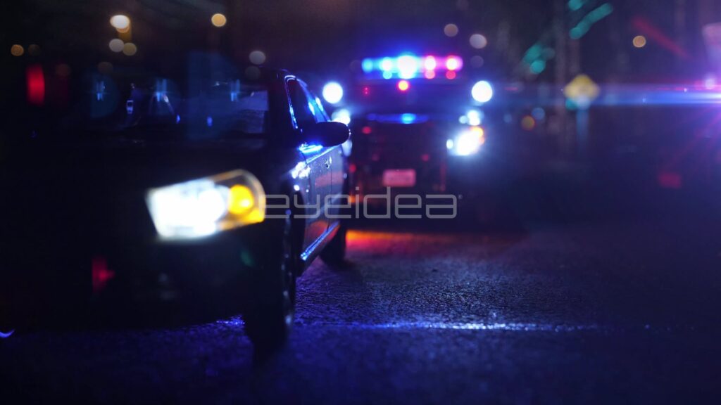 Car Headlights Beside a Police Stop with Flashing Lightbars