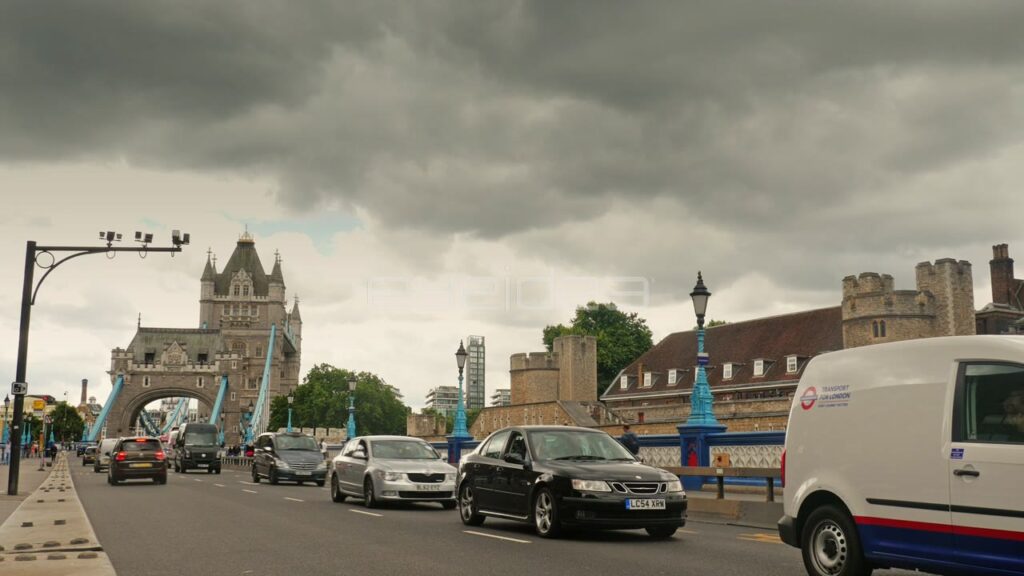 Traffic Approaching Tower Bridge Under Cloudy Sky