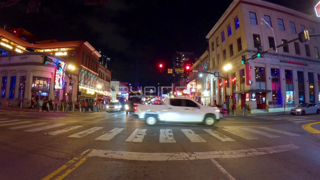 Pedestrians Cross Broadway Under Neon Signs at Night in Nashville