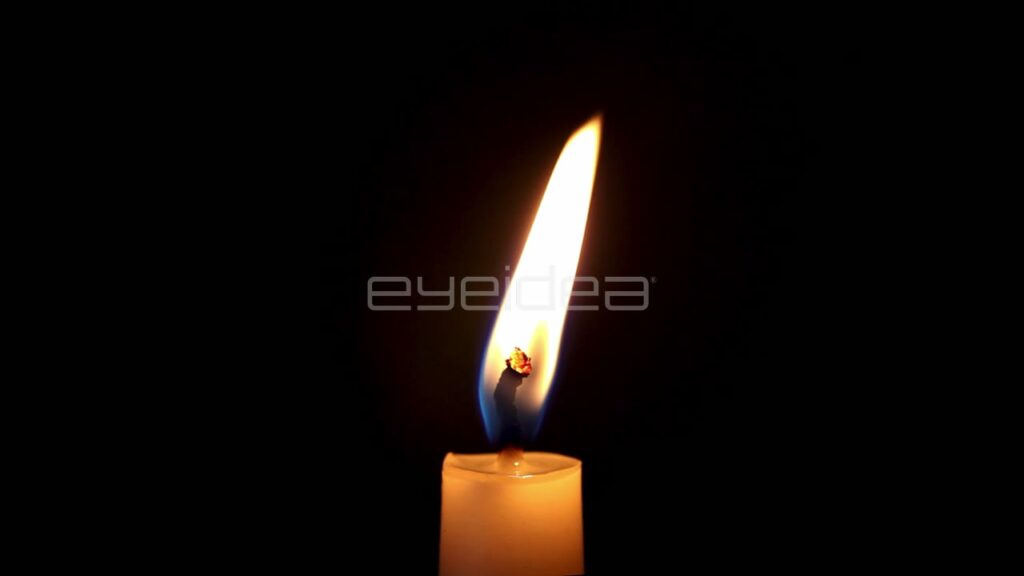Single Candle Flame Burning against a Black Background