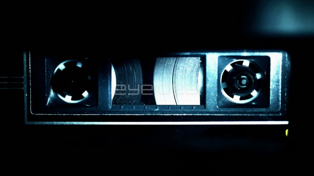 Macro Close-Up of Audio Cassette Tape Spinning in Blue Light