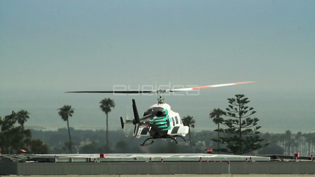 White and Teal Helicopter Taking Off from Rooftop Helipad