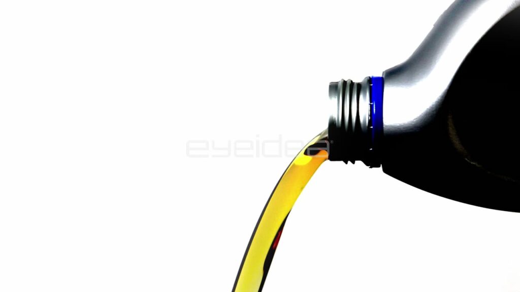 Golden Motor Oil Pouring from Black Plastic Bottle