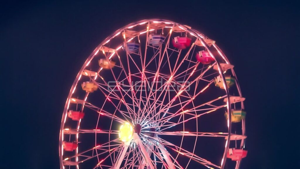 Rotating Ferris Wheel with Colorful Lights at Night