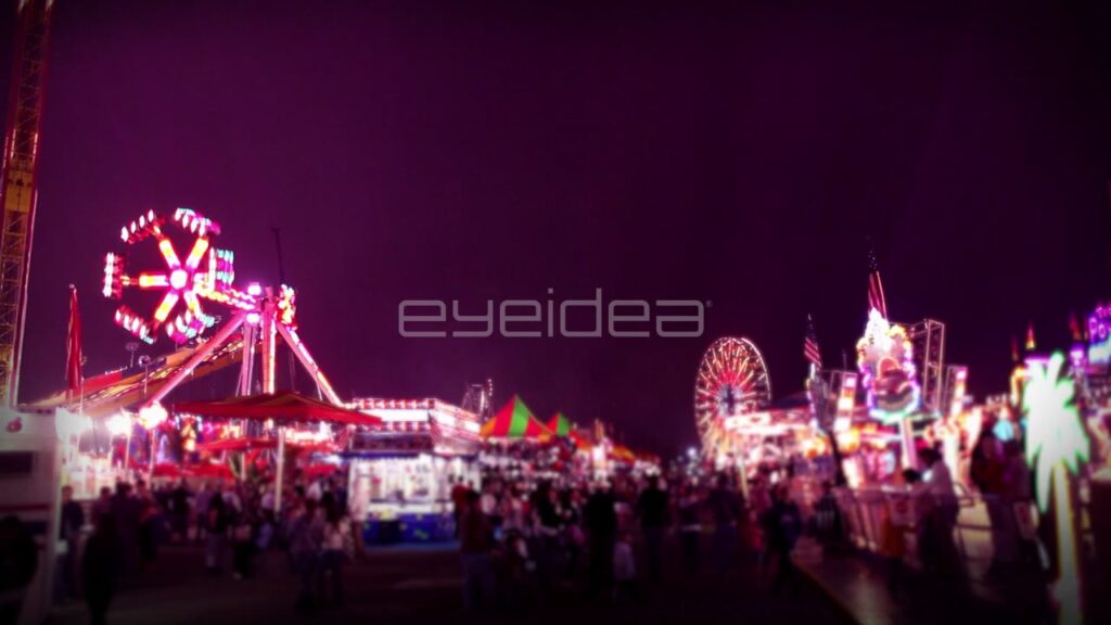 People Walking through Carnival Midway at Night with Pink Lighting